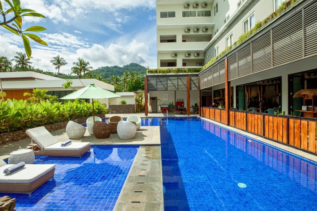 un hotel con una piscina con tumbonas y un edificio en Amani Suite and Apartment ZN41 en Senggigi 