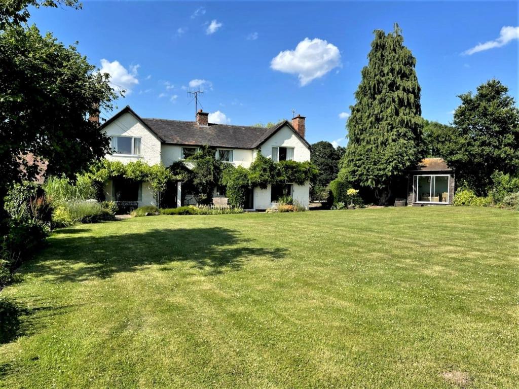 a white house with a large grass yard at 3 Bed in Great Malvern 90775 in Mathon