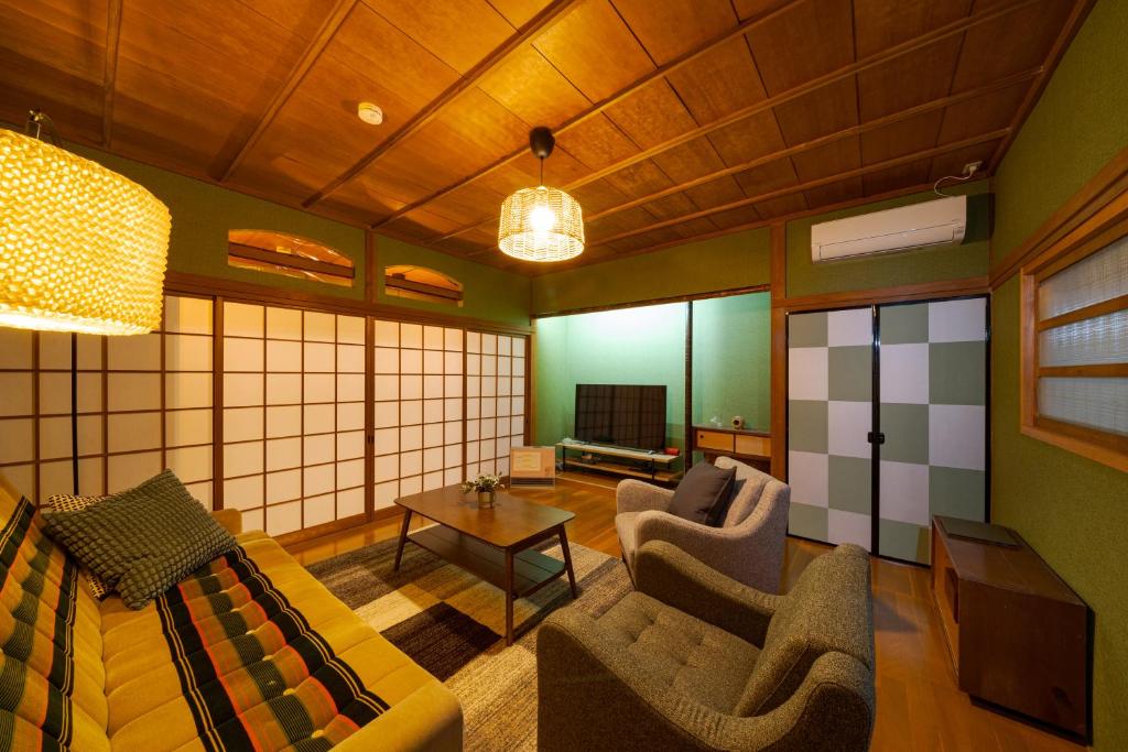 sala de estar con sofá, sillas y TV en Kamekawa Yukari Ann en Beppu