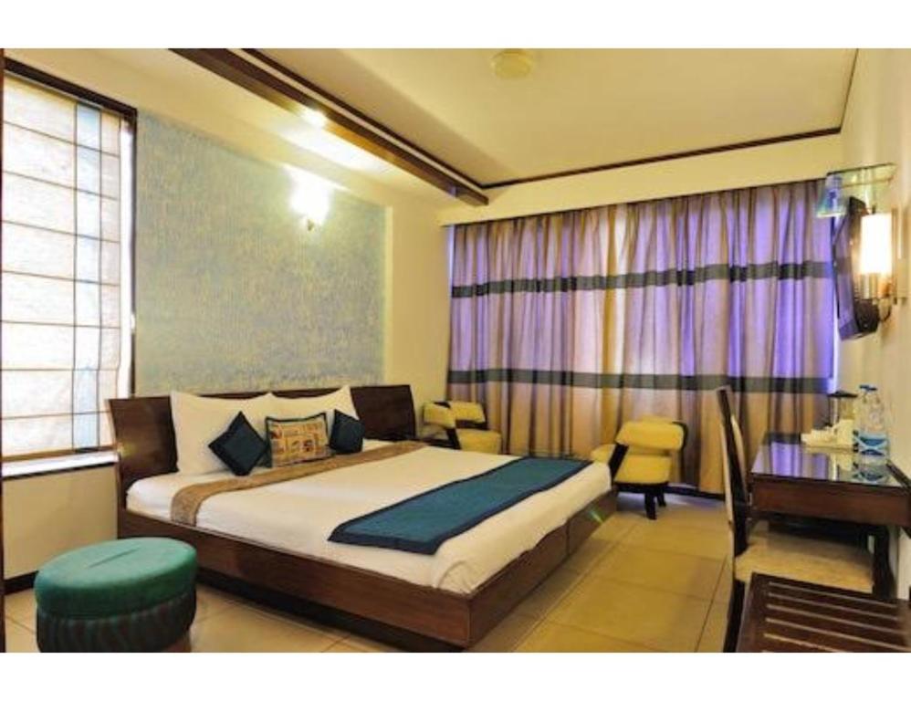 a bedroom with a bed and a table and a desk at Hotel The Tulip ,Chandigarh in Chandīgarh
