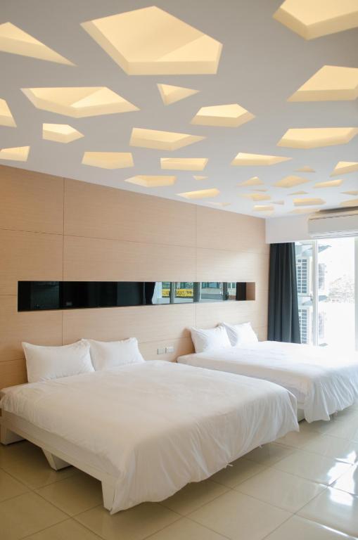 two beds in a hotel room with a ceiling with lights at Apple Tree Bed and Breakfast in Hualien City