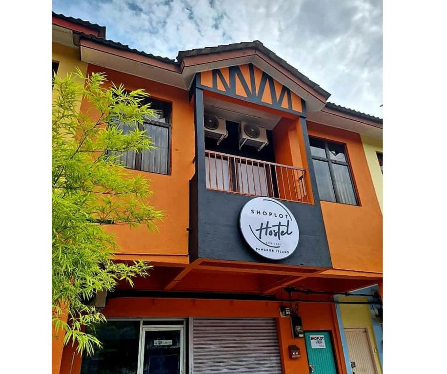ein orangefarbenes und schwarzes Gebäude mit einem Schild drauf in der Unterkunft ShopLot Hostel Pangkor in Kampong Pasir Bogak