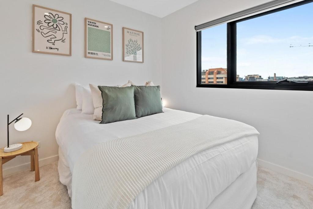 um quarto com uma grande cama branca e uma janela em Elegant Collingwood Apartment with City Views em Melbourne