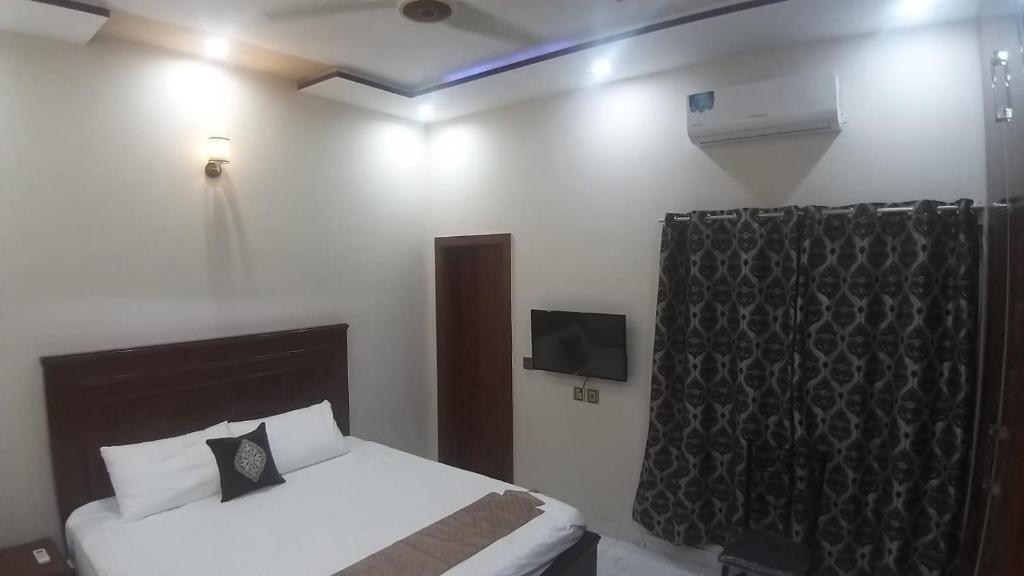 ein Schlafzimmer mit einem Bett und einem TV an der Wand in der Unterkunft 5-Bedroom Vacation Home in Lahore