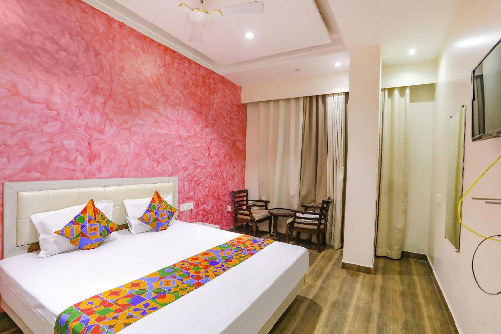 a bedroom with a bed and a pink wall at FabHotel Uday Villa in Kānpur