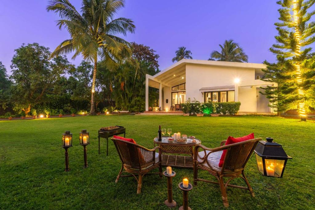 a table and chairs in front of a house at The Beach House by StayVista with Modern interiors, nearby beach, pool, lawn in Alibaug