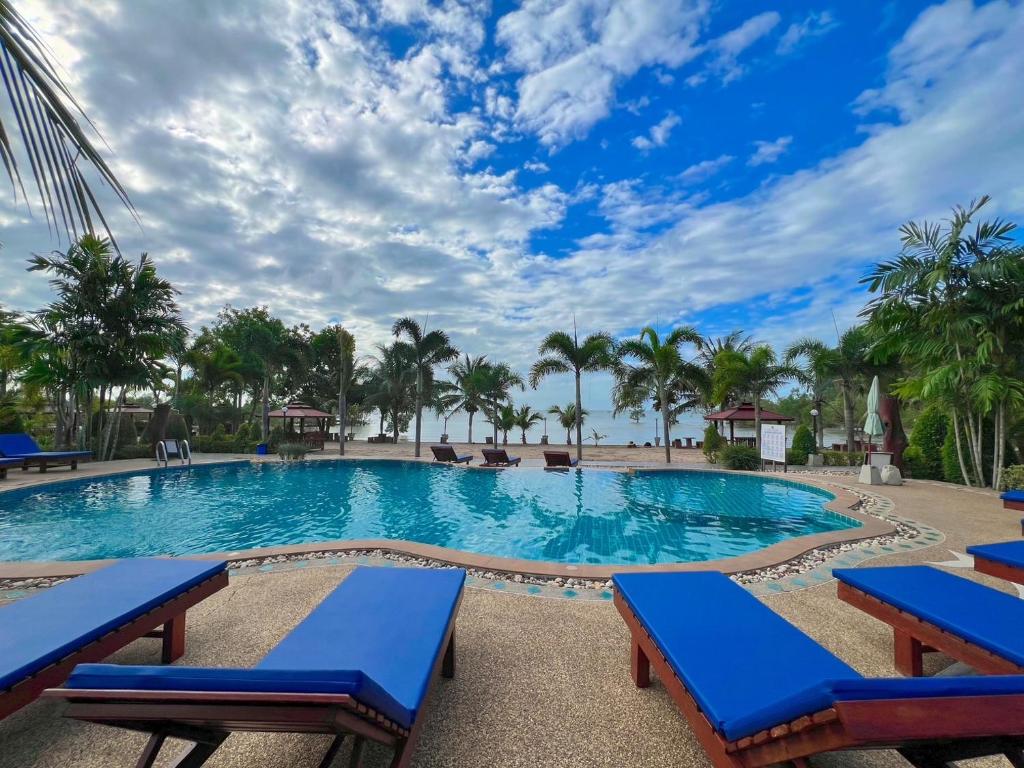 una piscina en el complejo con bancos azules y palmeras en Diamond Beach Resort, en Ao Nam Mao