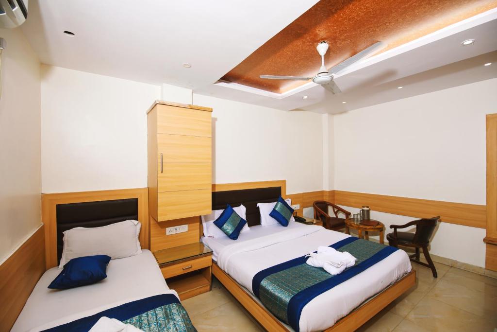 Hotel Lav-Kush في نيودلهي: غرفة نوم بسريرين ومروحة سقف