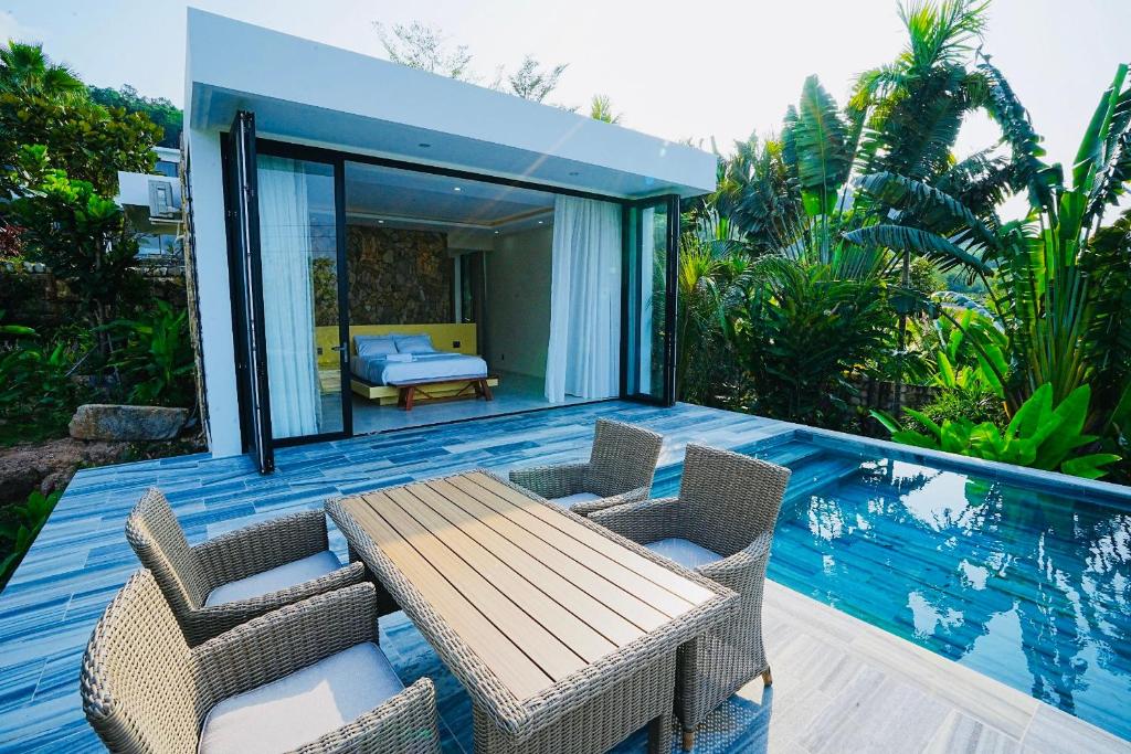 una casa con una mesa de madera y sillas en una terraza en Kiwuki Beachfront Villa en Phu Quoc