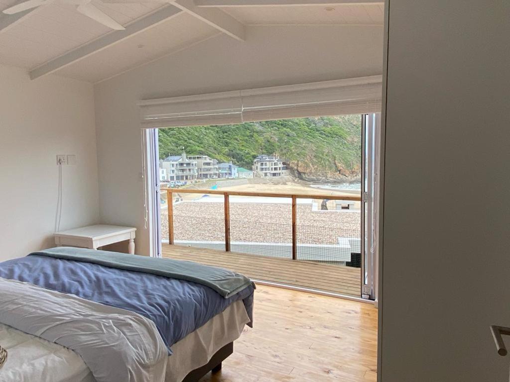 a bedroom with a bed and a large window at MakiSaki Beach House in Herolds Bay