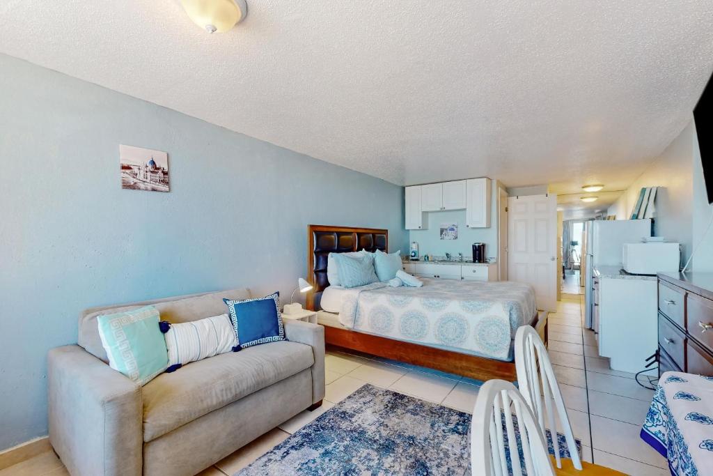 a bedroom with a bed and a couch and a kitchen at Pirates Cove Unit G22 in Daytona Beach