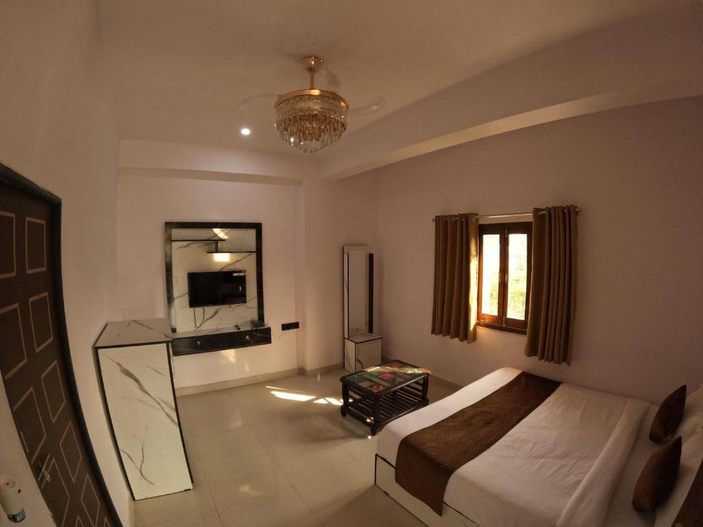een slaapkamer met een bed, een televisie en een spiegel bij Marcol a countryside villa in Udaipur