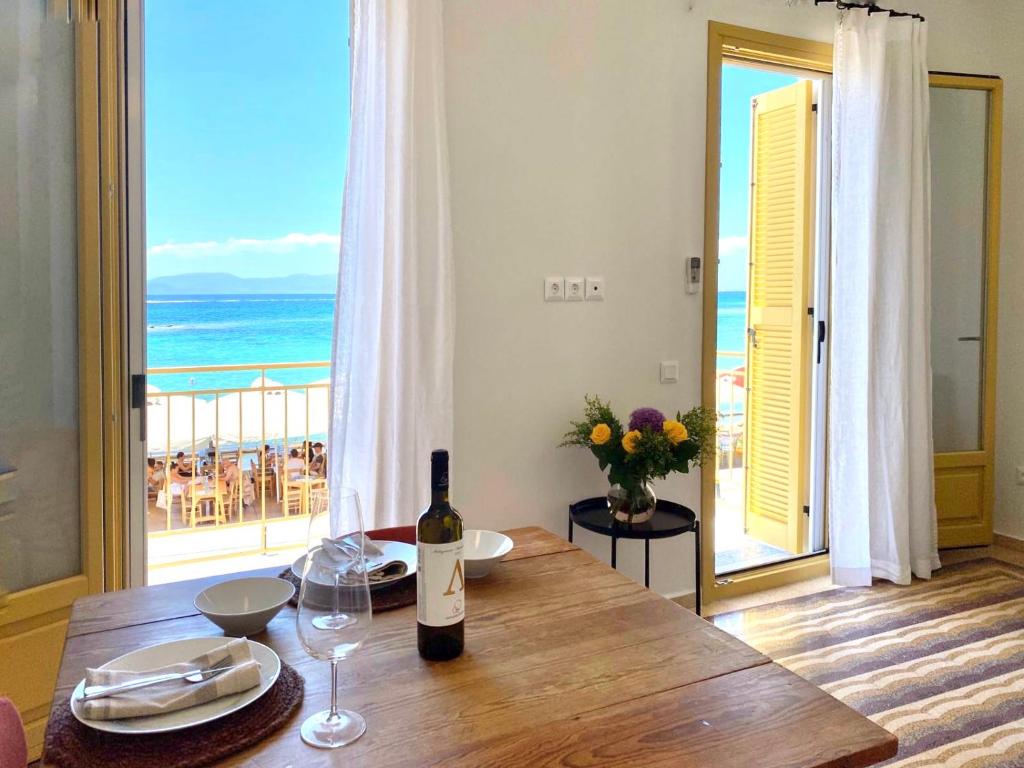 a bottle of wine on a wooden table with a view of the ocean at Port view apartment Aegina in Aegina Town