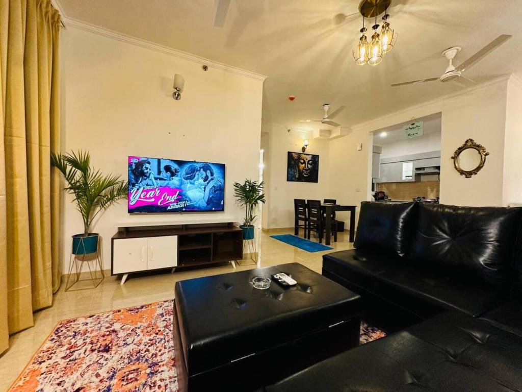 een woonkamer met een zwarte bank en een flatscreen-tv bij Celestial Chic Suite With Swimming Pool in Lucknow