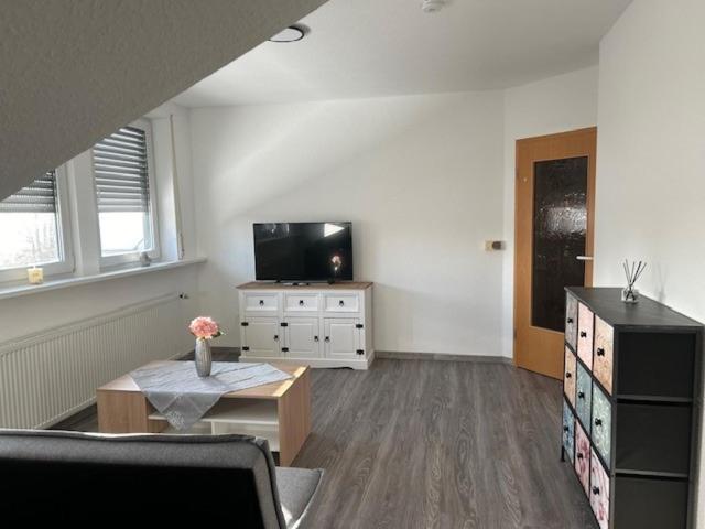 a living room with a flat screen tv and a table at Appartement 6 in Hilter in Hilter am Teutoburger Wald