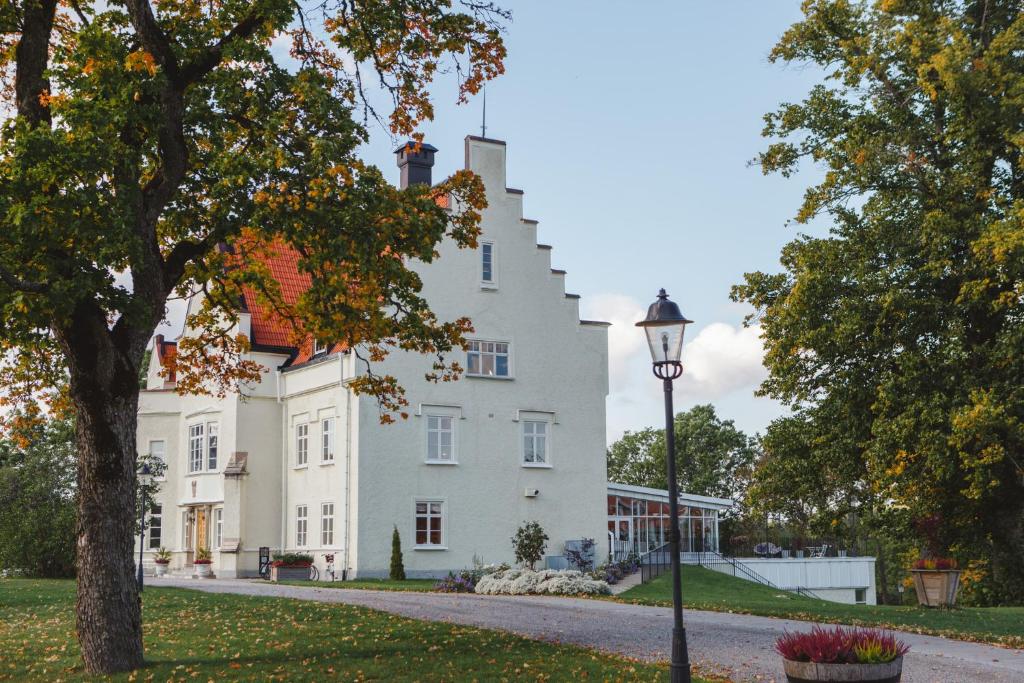 una casa blanca con una luz de la calle delante de ella en Vidbynäs Gård & Konferens, en Nykvarn