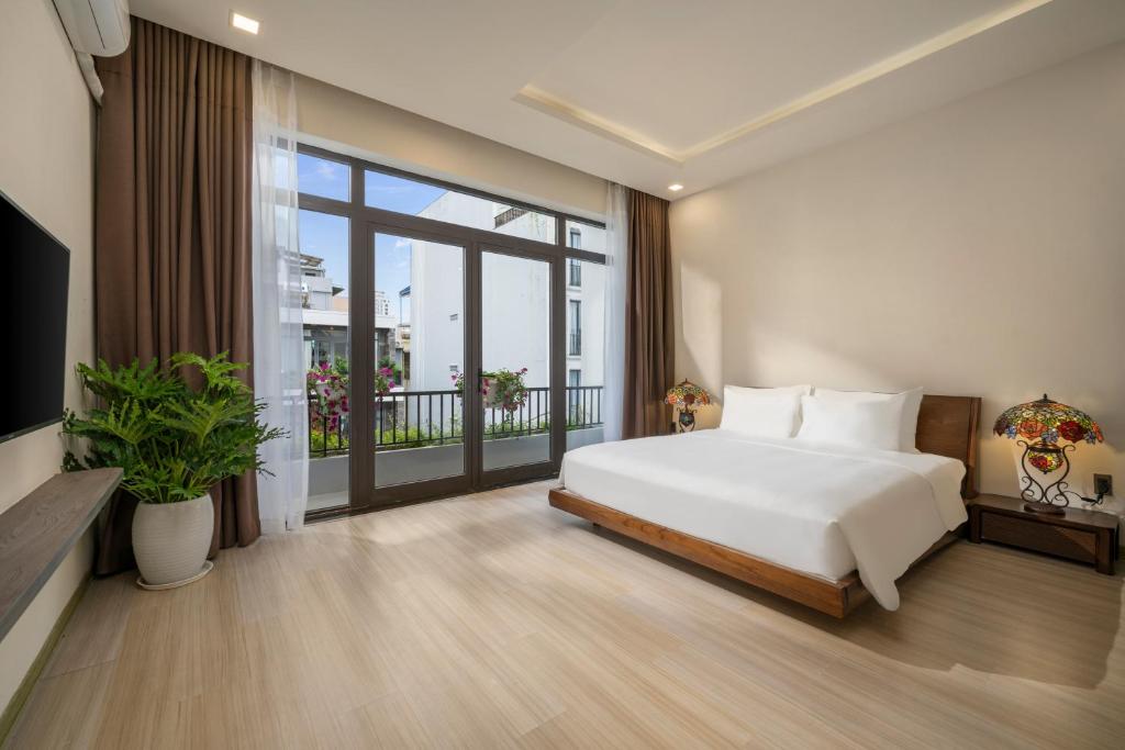 a bedroom with a white bed and a balcony at Tashi Apartment in Da Nang