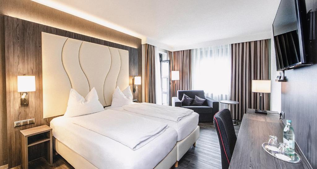 een hotelkamer met een wit bed en een bureau bij PLAZA Hotel Buchhorner Hof in Friedrichshafen