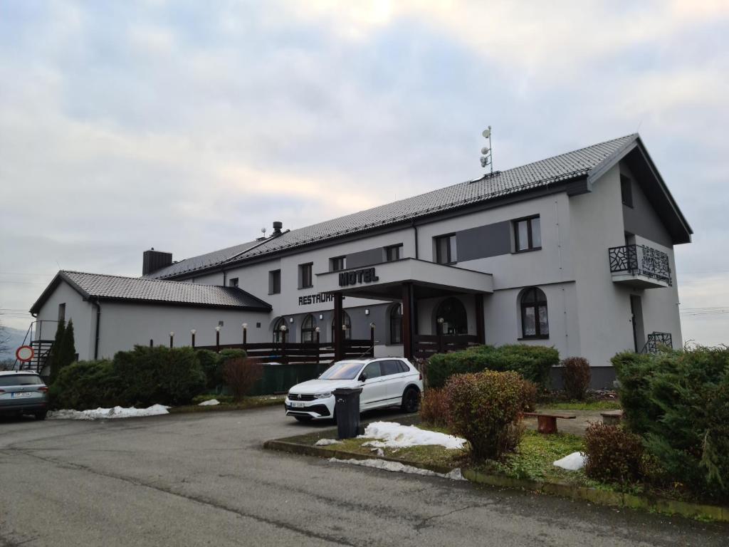 ein weißes Gebäude mit einem davor geparkt in der Unterkunft Motel Tošanovice in Dolní Tošanovice