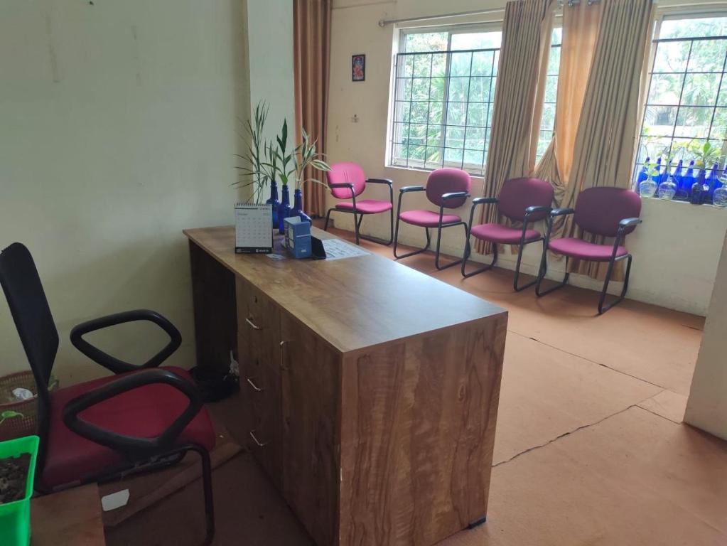 poczekalnia z różowymi krzesłami i biurkiem w obiekcie SPOT ON SB Guest House w mieście Alappuzha