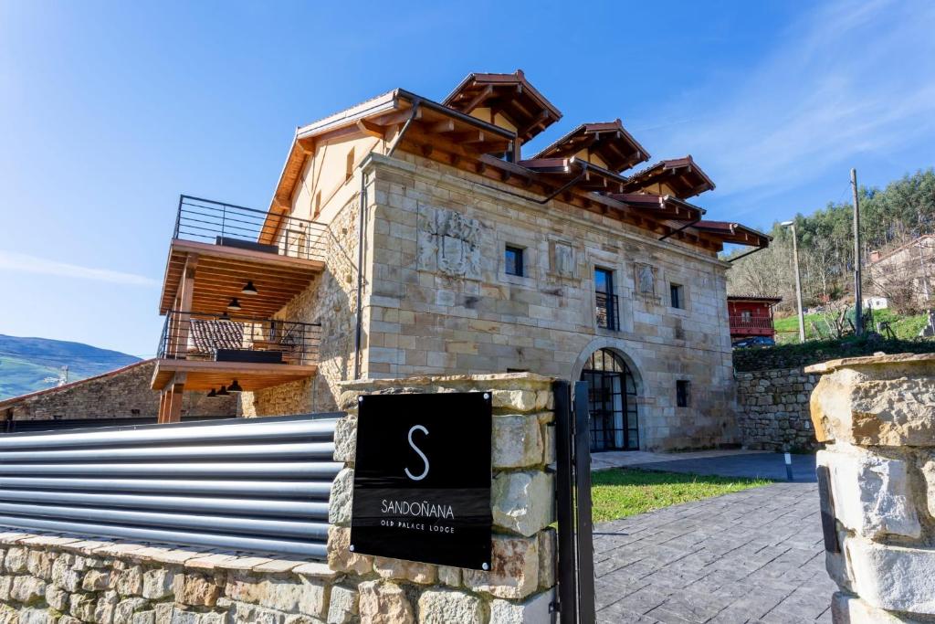 Villafufre的住宿－Sandoñana Old Palace Lodge，一座石头建筑,前面有标志