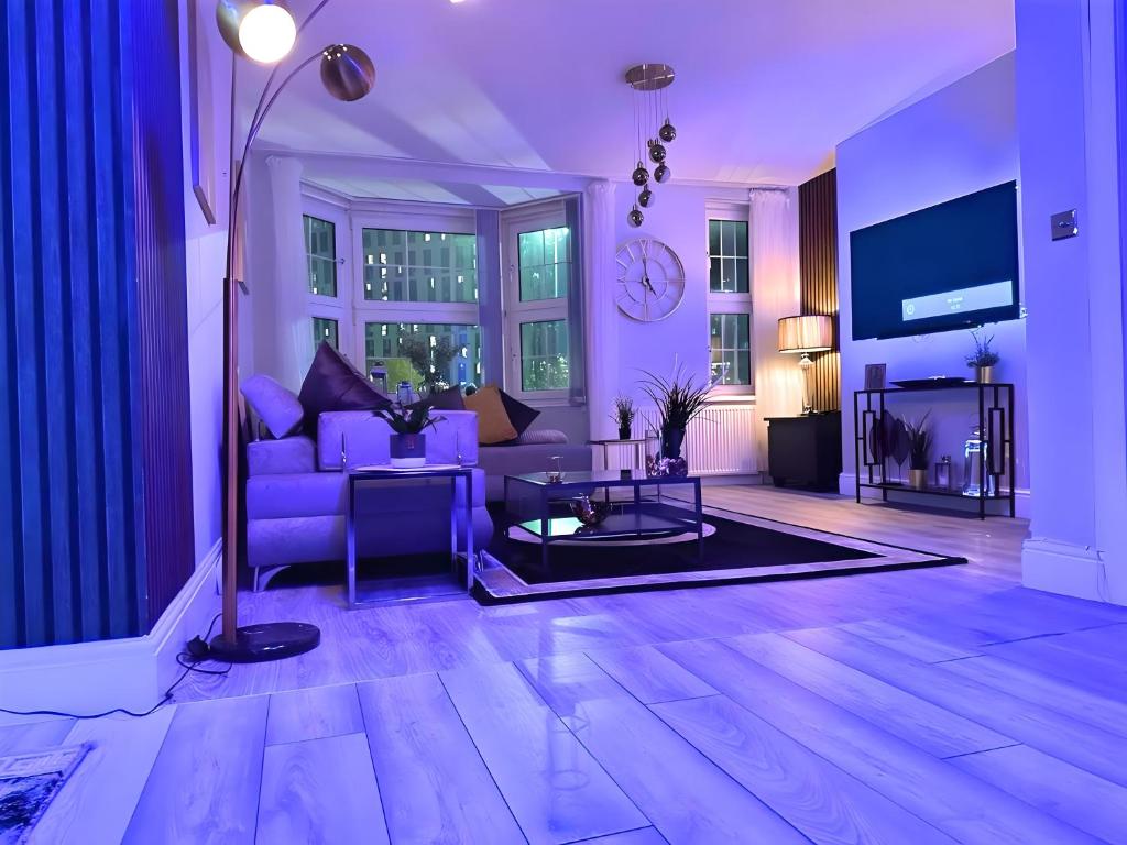 ein Wohnzimmer mit einem lila Sofa und einem Tisch in der Unterkunft *Luxury 9ine Lush Jacuzzi Apartment & Balcony* in Birmingham