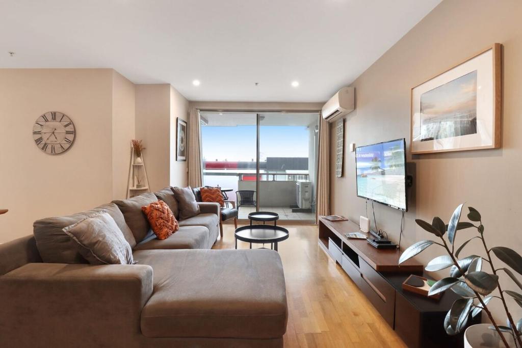 a living room with a couch and a tv at Terminus Apartment I Steps from Geelongs Buzz in Geelong