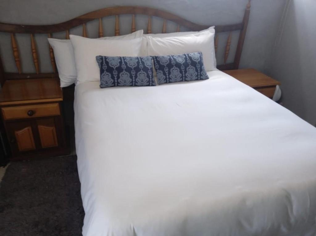 a white bed with two pillows on top of it at Nasrec Guesthouse in Johannesburg