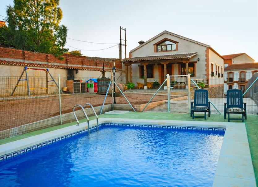 una piscina con 2 sillas junto a una casa en Casa Rural El Olivar del Puerto en Cabañeros, en Horcajo de los Montes