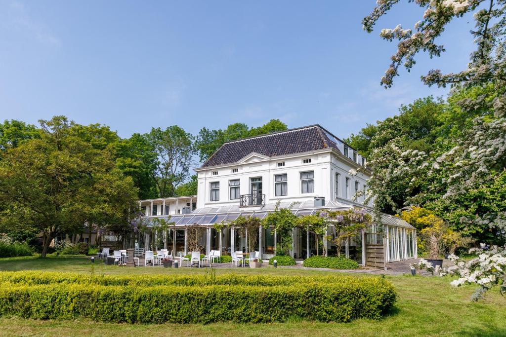 a white house with tables and chairs in a yard at Buitenplaats Iepenoord in Oostkapelle