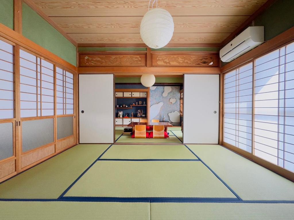 Habitación japonesa con suelo de moqueta y ventanas en Shachihoko 海辺の一棟貸切ヴィラ しゃちほこ en Imari