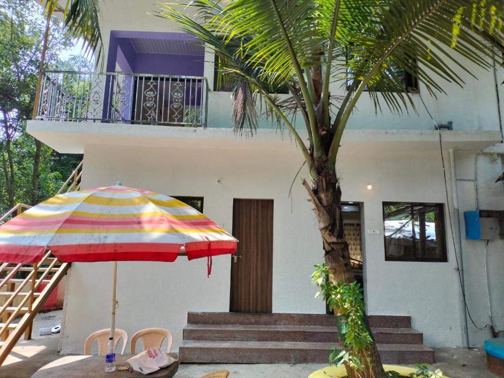 a colorful umbrella and a palm tree in front of a house at Vellankani Resort Gorai in Mumbai