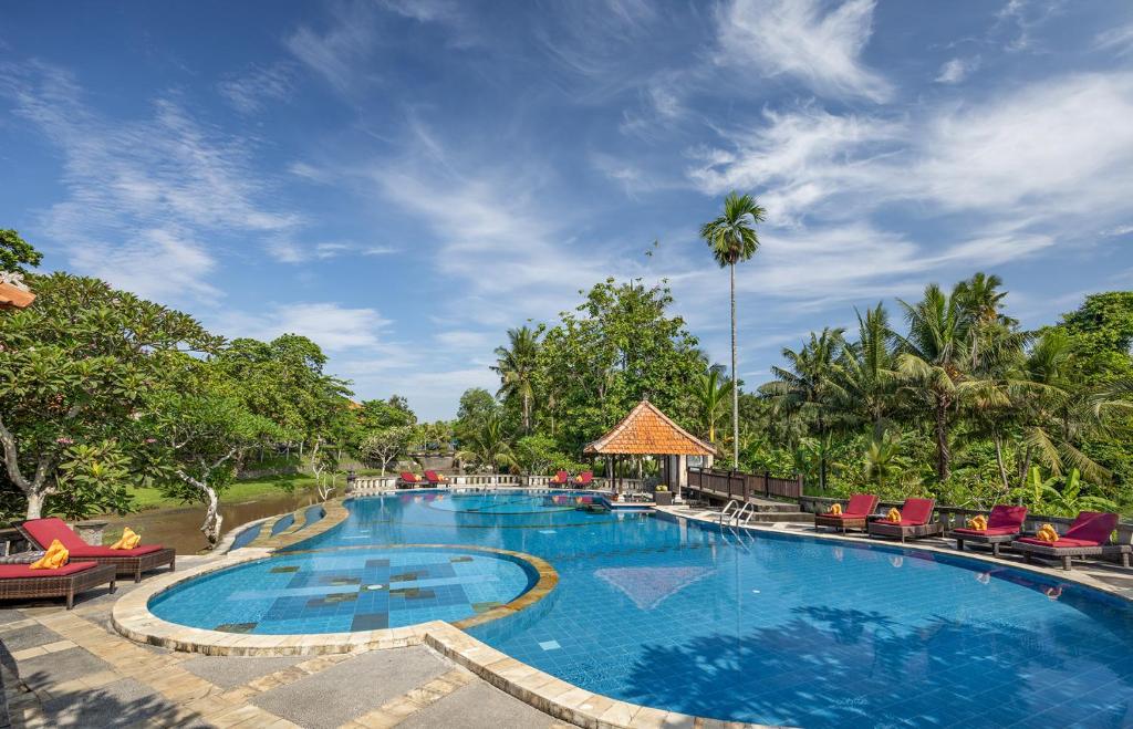 una piscina en un complejo con sillas y árboles en Santi Mandala Villa & Spa en Sukawati