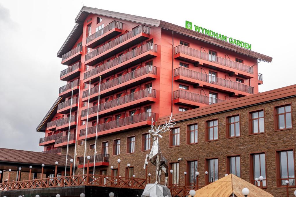 a red building with a statue in front of it at Wyndham Garden Burabay in Borovoye