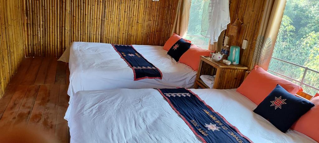 two beds in a room with a window at Bình Minh Homestay in Nam Giang