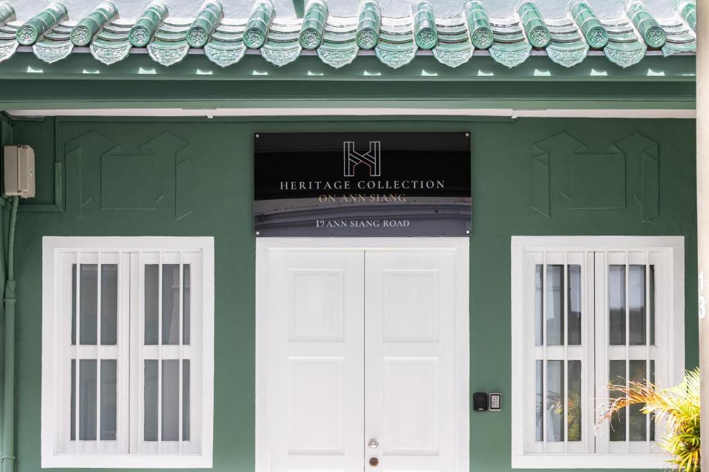 a green building with a white door and two windows at NEWLY REFURBISHED - Heritage Collection on Ann Siang in Singapore