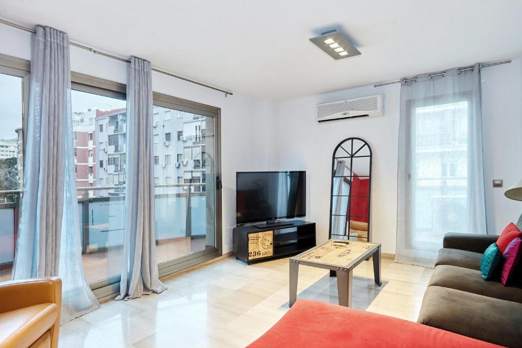 a living room with a tv and large windows at Piso Jaén Calle La Luna in Jaén