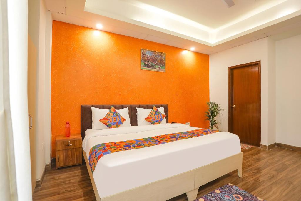 1 dormitorio con 1 cama grande y pared de color naranja en FabHotel Spark Inn I, en Gurgaon