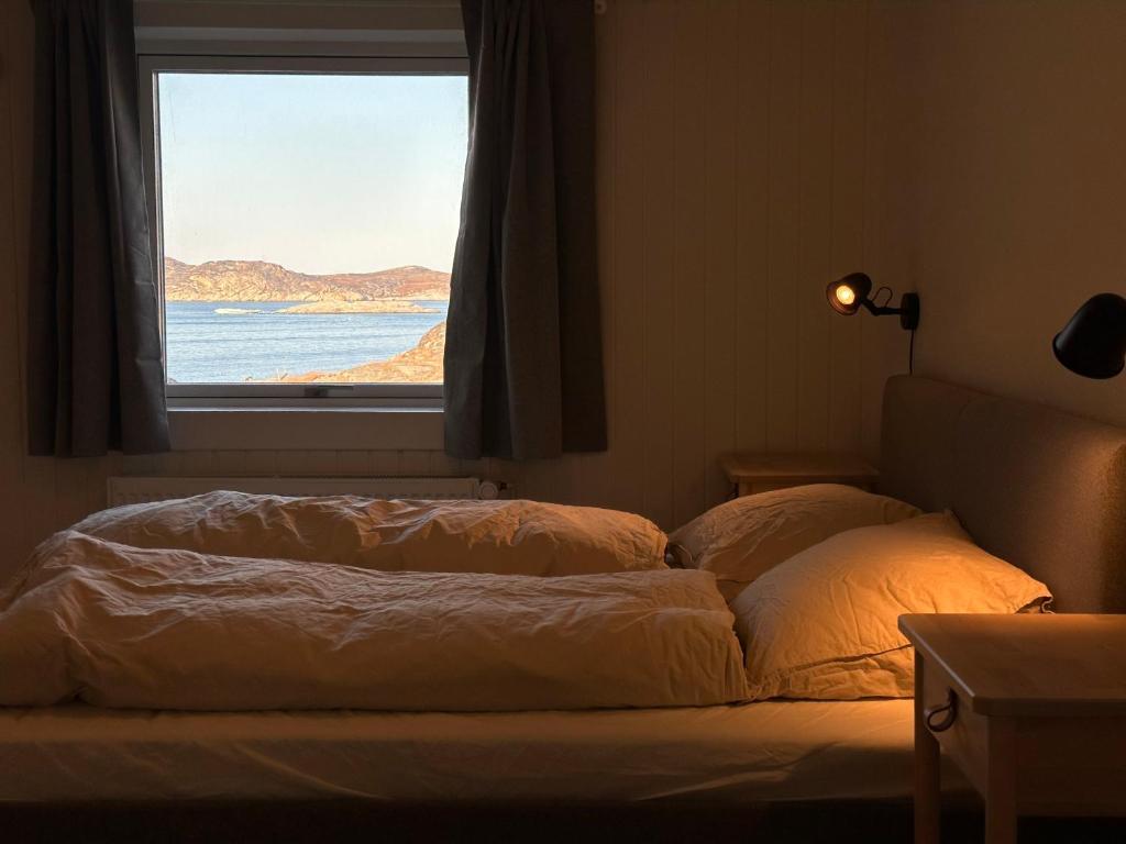 Bett in einem Zimmer mit Fenster in der Unterkunft Grand seaview vacation house, Ilulissat in Ilulissat