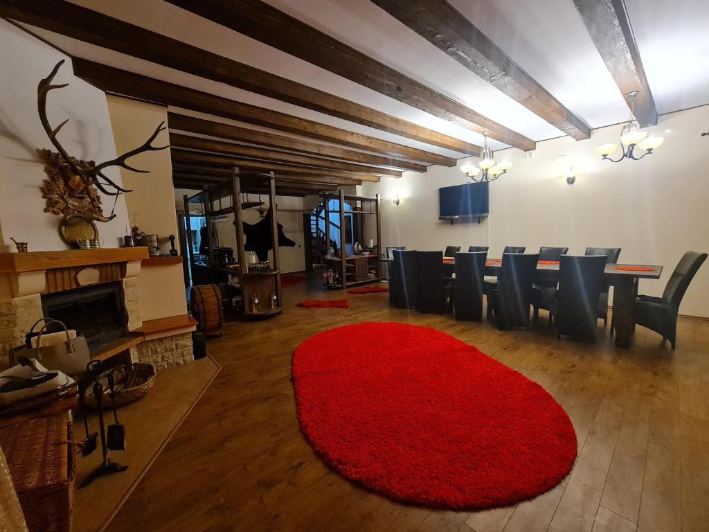 sala de estar con alfombra roja, mesa y sillas en Vila de la Munte Tihuta, en Piatra Fântânele