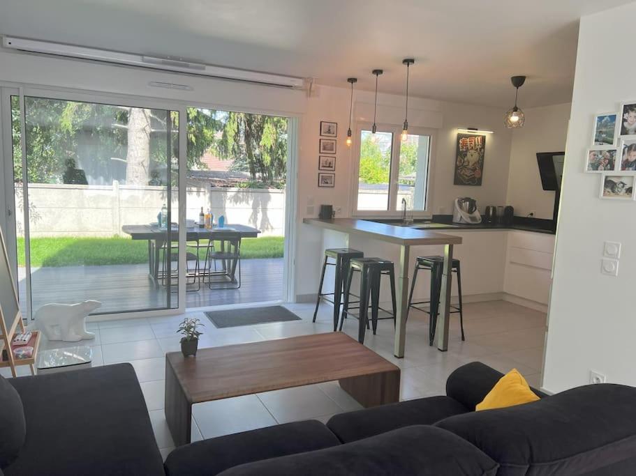 un salon et une cuisine avec un canapé et une table dans l'établissement Maison moderne à 25 minutes du centre Paris et JO 2024, à Eaubonne