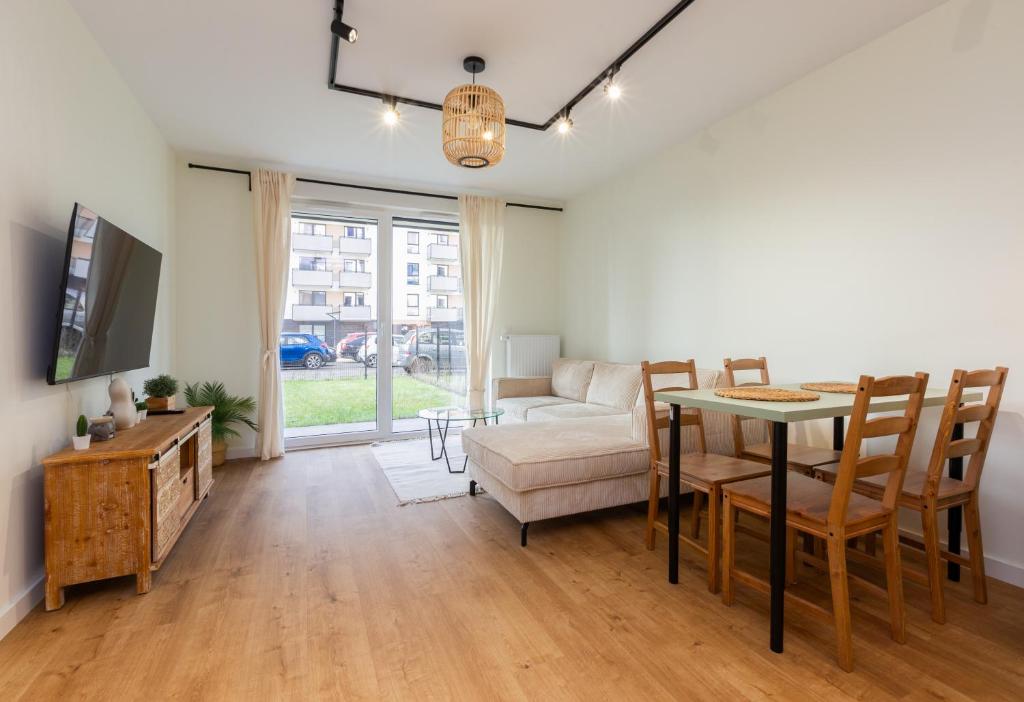 a living room with a table and a couch at Letnicka Cosy Apartment with Garden in Gdańsk