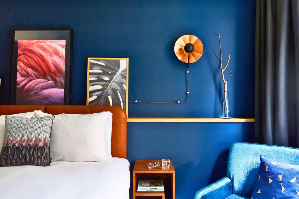 アントワープにあるホテル インディゴ アントワープ シティセンターの青い壁のベッドルーム(ベッド1台、椅子付)