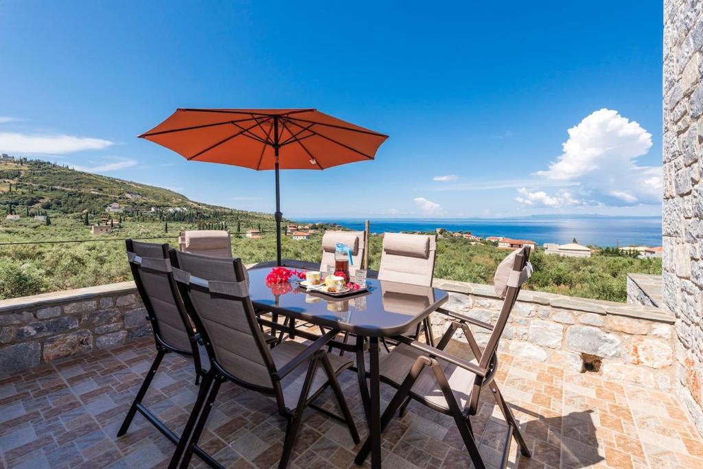 a table and chairs with an umbrella on a patio at Mani's Best Kept Secret - Seaview Villa Lida in Agios Nikolaos