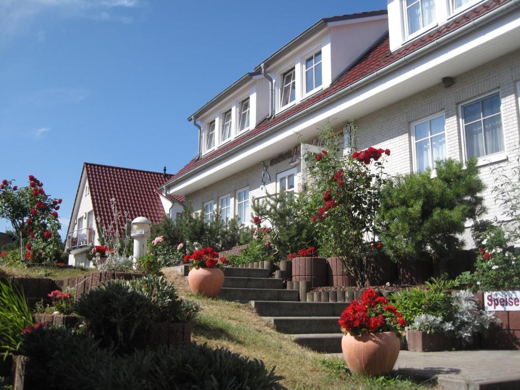 a house with potted plants and flowers on the stairs at Aparthotel Leuchtfeuer Rügen in Glowe