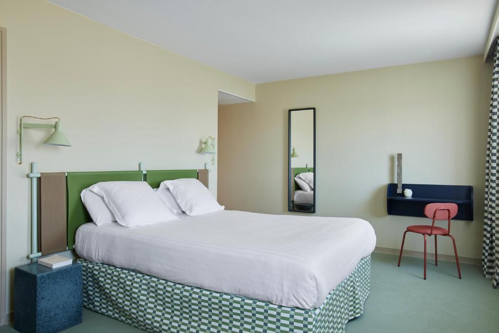 カンヌにあるHotel des Victoiresのベッドルーム1室(大型ベッド1台、赤い椅子付)