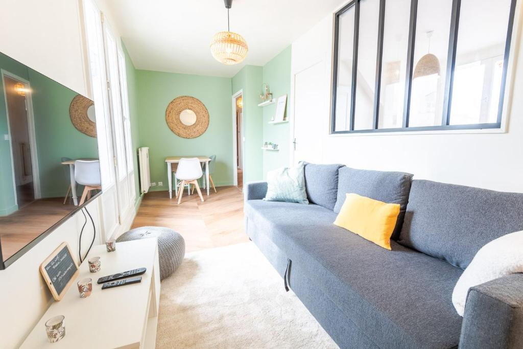 un salon avec un canapé bleu et une table dans l'établissement Le Cozy-Tours - Charmant appart en centre-ville, à Tours