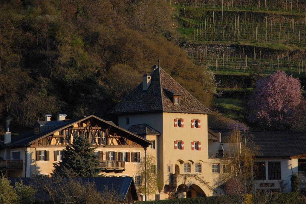 ein großes weißes Gebäude mit schwarzem Dach in der Unterkunft Weingut Köfelgut - Turris Vini in Kastelbell