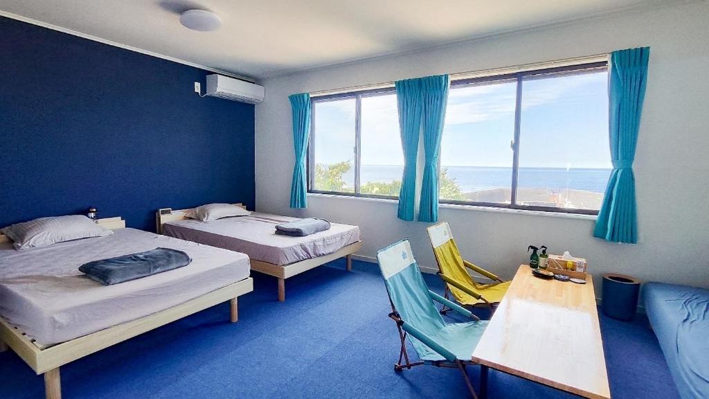 a room with two beds and a table and a chair at QUENOS in Oshima