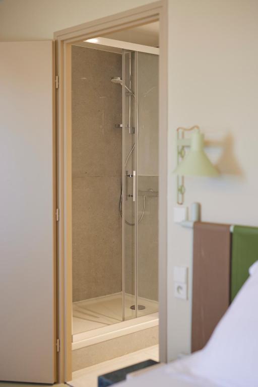 a glass shower stall in a room with a bed at Hotel des Victoires - Restaurant in Cannes